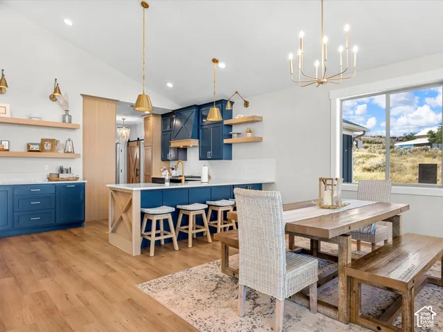 Vaulted ceiling with recessed lighting, wood-finish flooring, and a kitchen island with seating