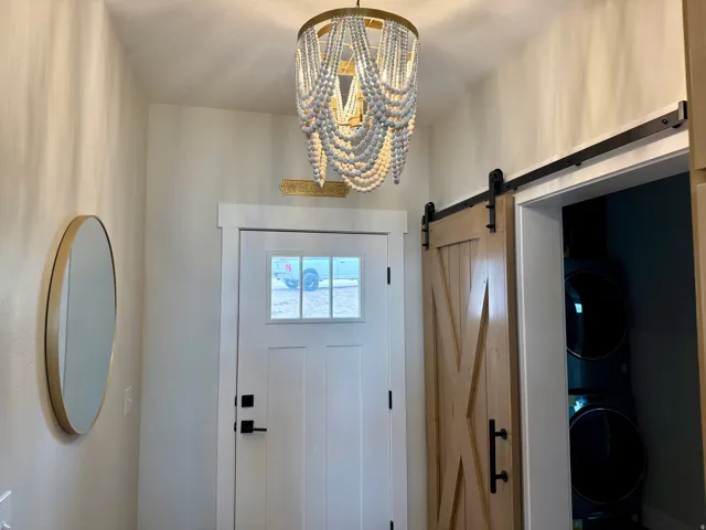 Entrance foyer featuring a barn door, suspended lighting, and stacked washing machine and dryer