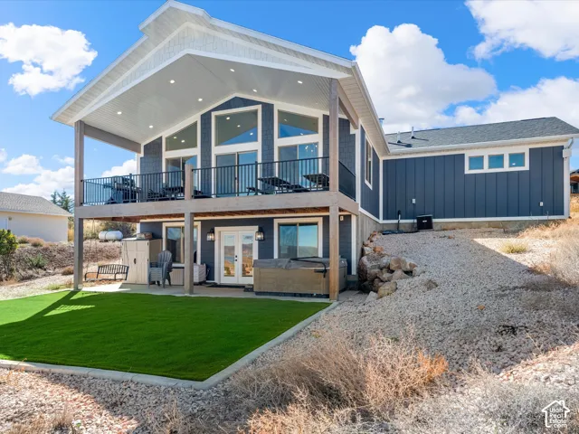 Two-story exterior with a covered upper deck, lower patio, and a sloped, xeriscaped landscape