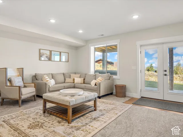 Recessed lighting illuminates this living area featuring carpeting, a large window, and double glass-paneled doors with direct outdoor access
