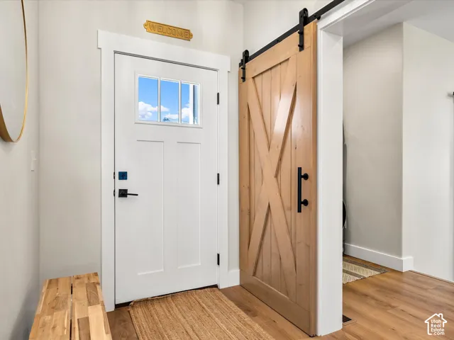Entryway featuring a white door with transom lites, matte black hardware, and wood-finish flooring