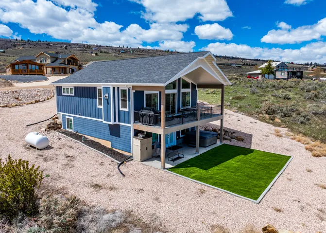 View of front of house with a patio, board and batten siding, a shingled roof, a front yard, and a wooden deck