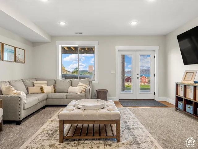 Dual French doors, recessed ceiling lighting, a large window, and light wood-finish flooring