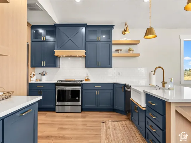 Modern kitchen featuring blue cabinetry, white subway tile backsplash, stainless steel appliances, and a farmhouse sink