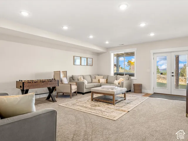 Recessed lighting illuminates the carpeted living space with a large window and double glass doors