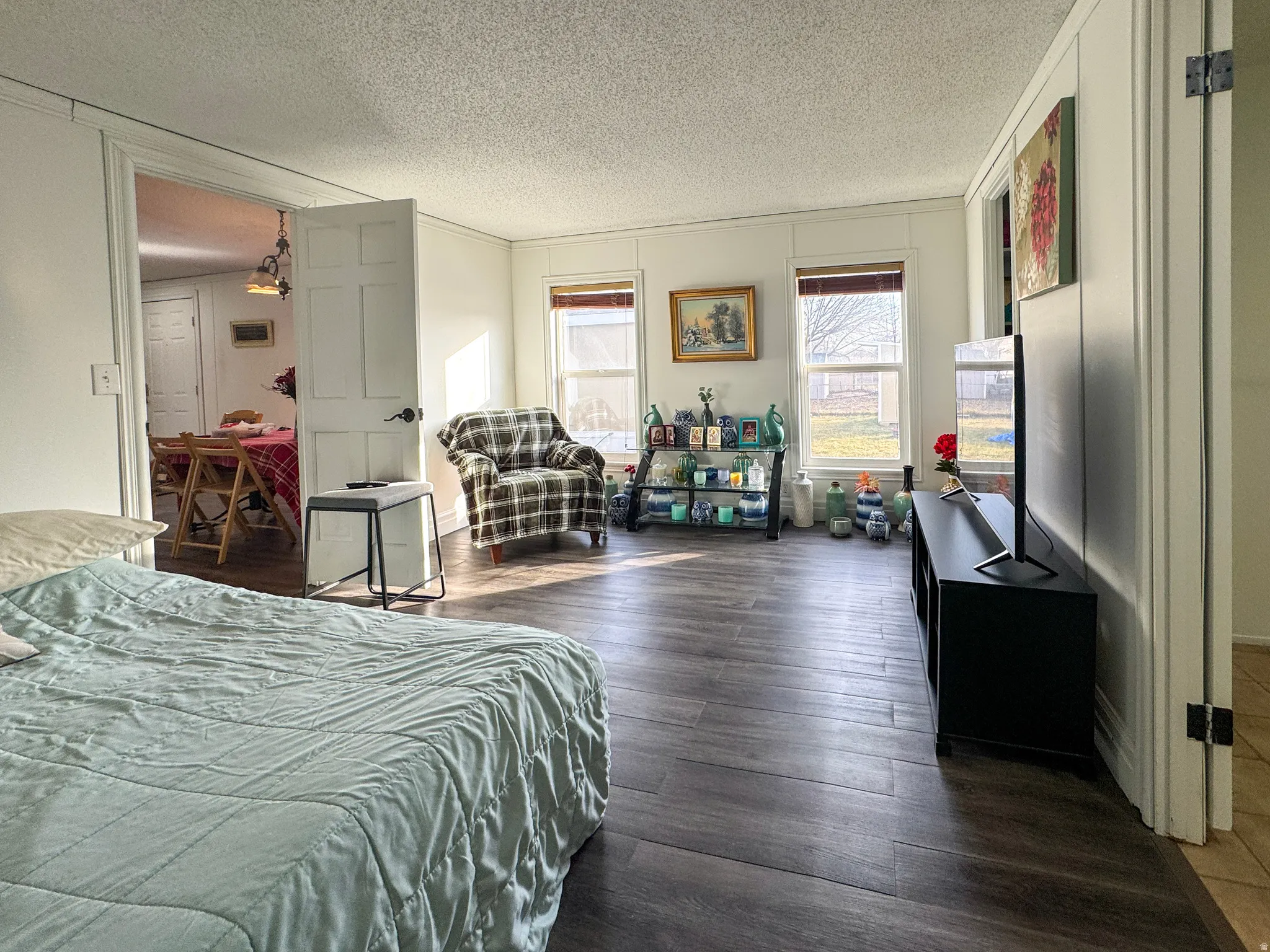 Bedroom with dark wood-style flooring, a decorative wall, a textured ceiling, and crown molding