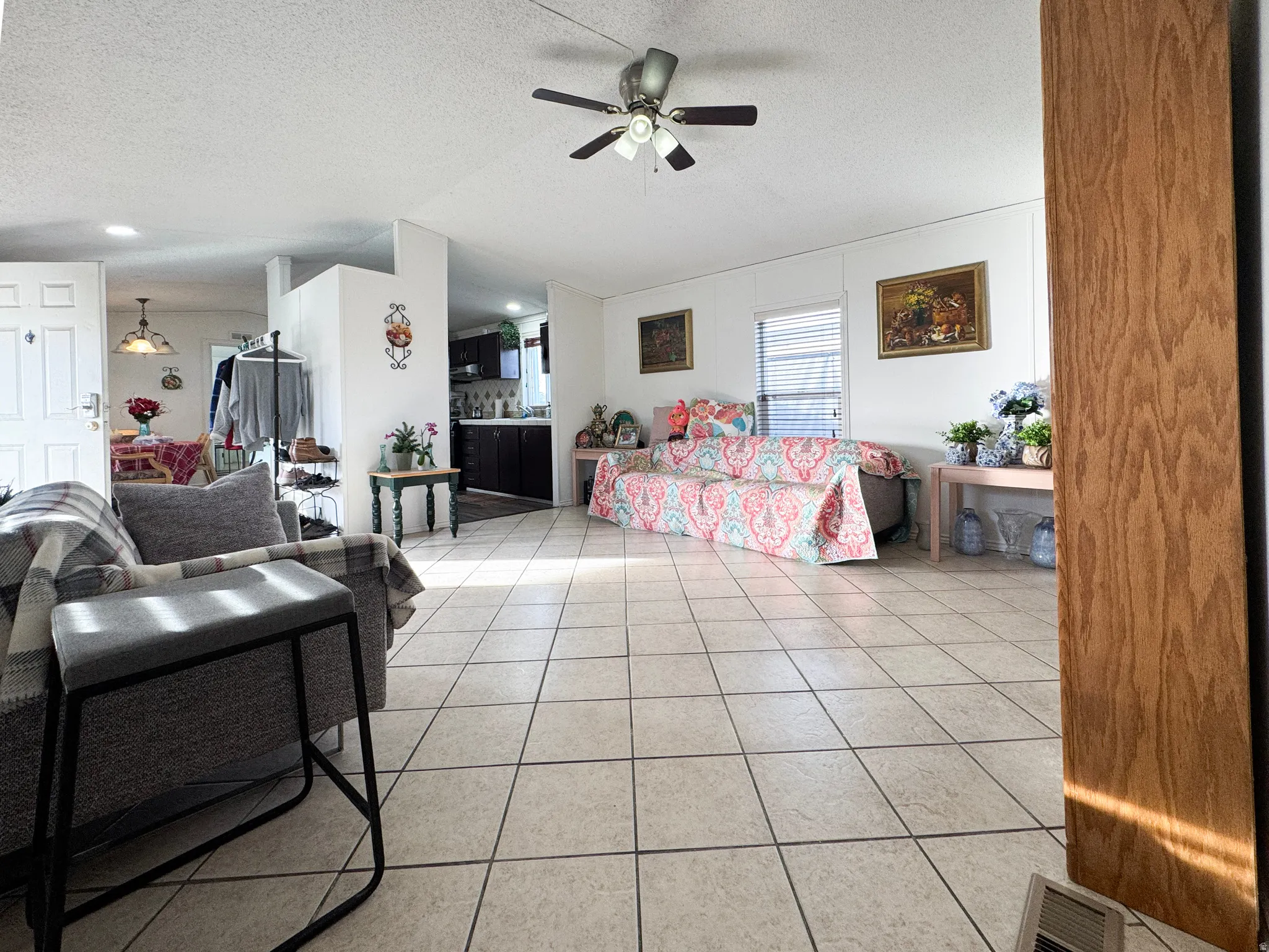 Living area featuring a textured ceiling, light tile patterned flooring, and ceiling fan