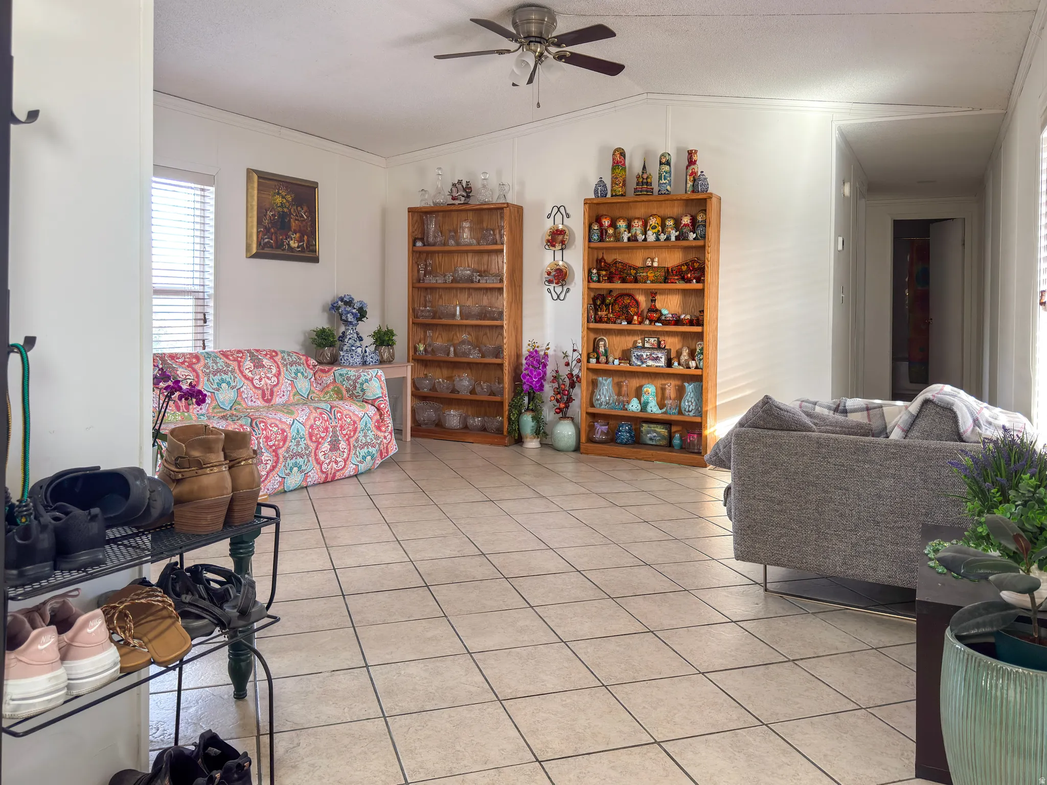 Living room featuring lofted ceiling, ceiling fan, crown molding, and light tile patterned floors