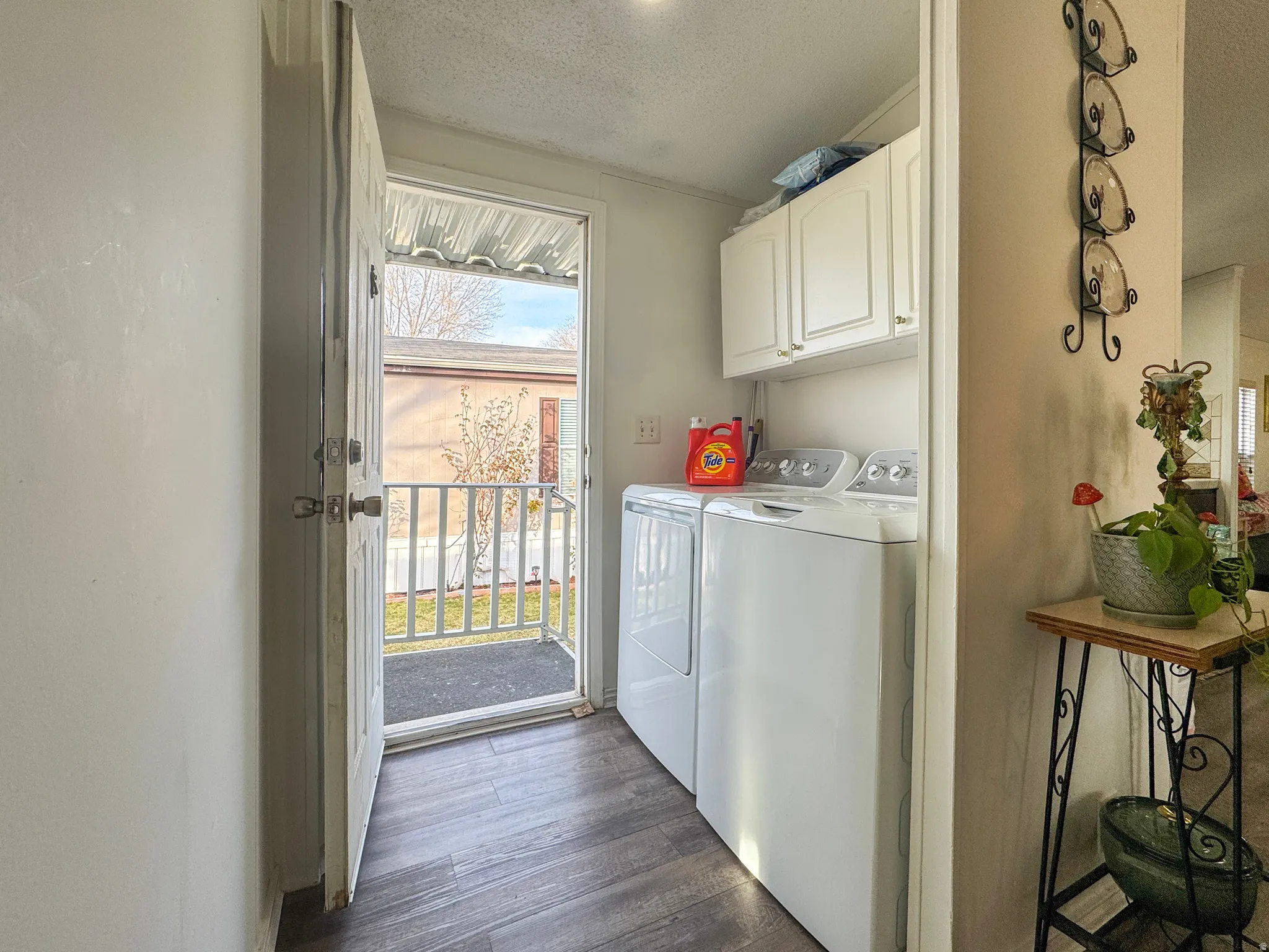 Laundry area with cabinet space, a textured ceiling, washer and clothes dryer, and dark wood-type flooring