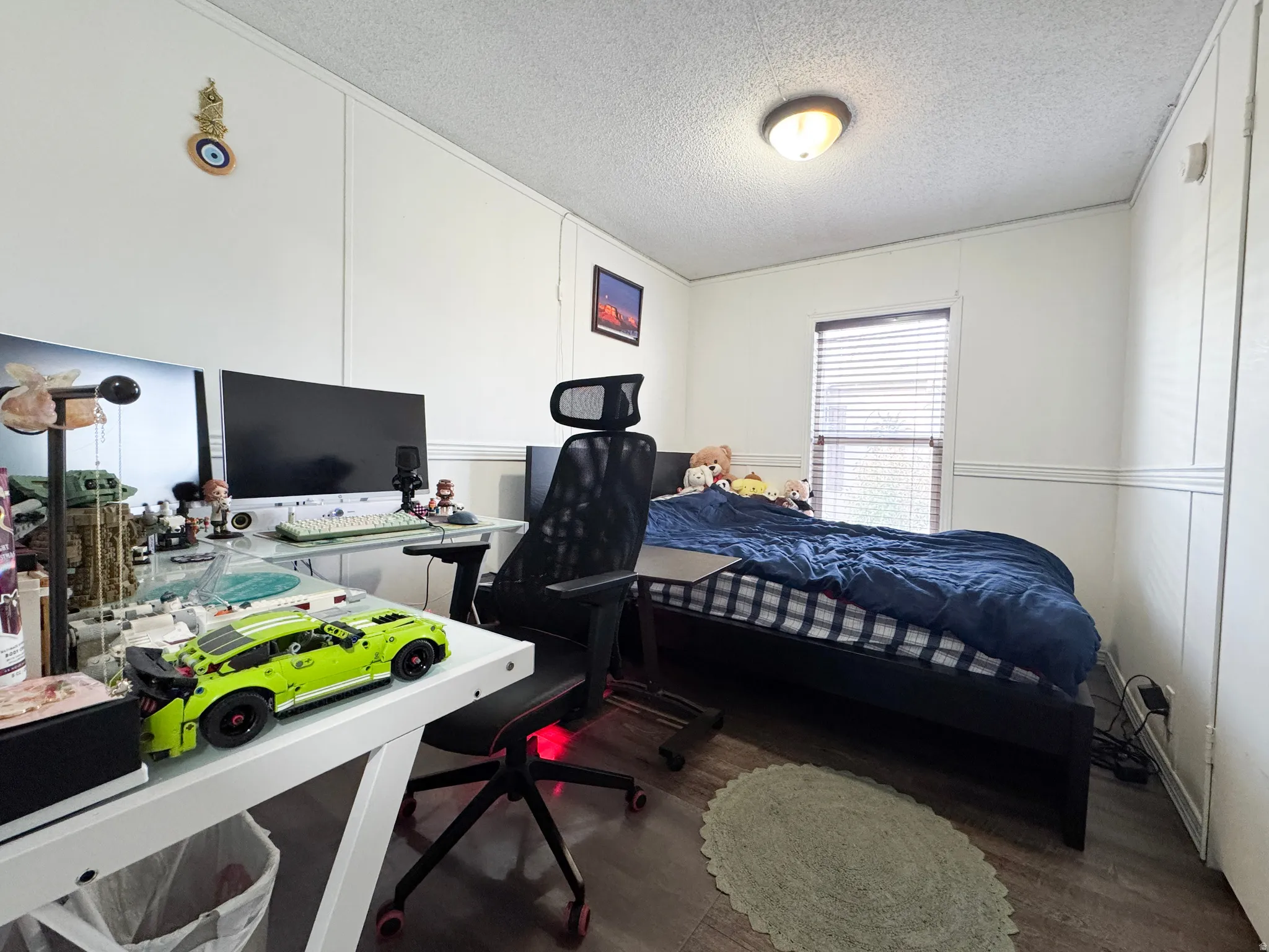 Bedroom featuring a textured ceiling, dark wood-style flooring, a desk, and a decorative wall