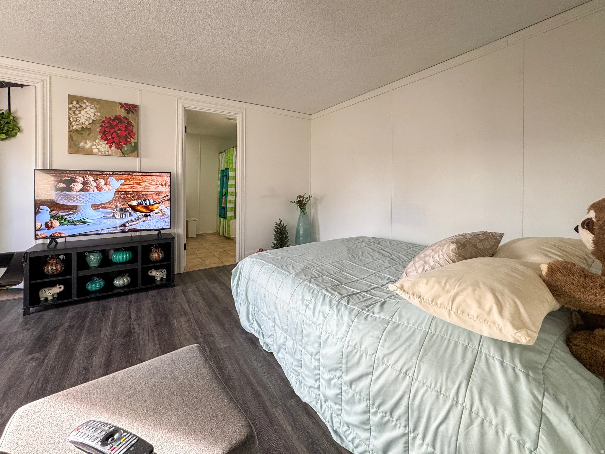 Bedroom featuring a textured ceiling, wood finished floors, and a decorative wall