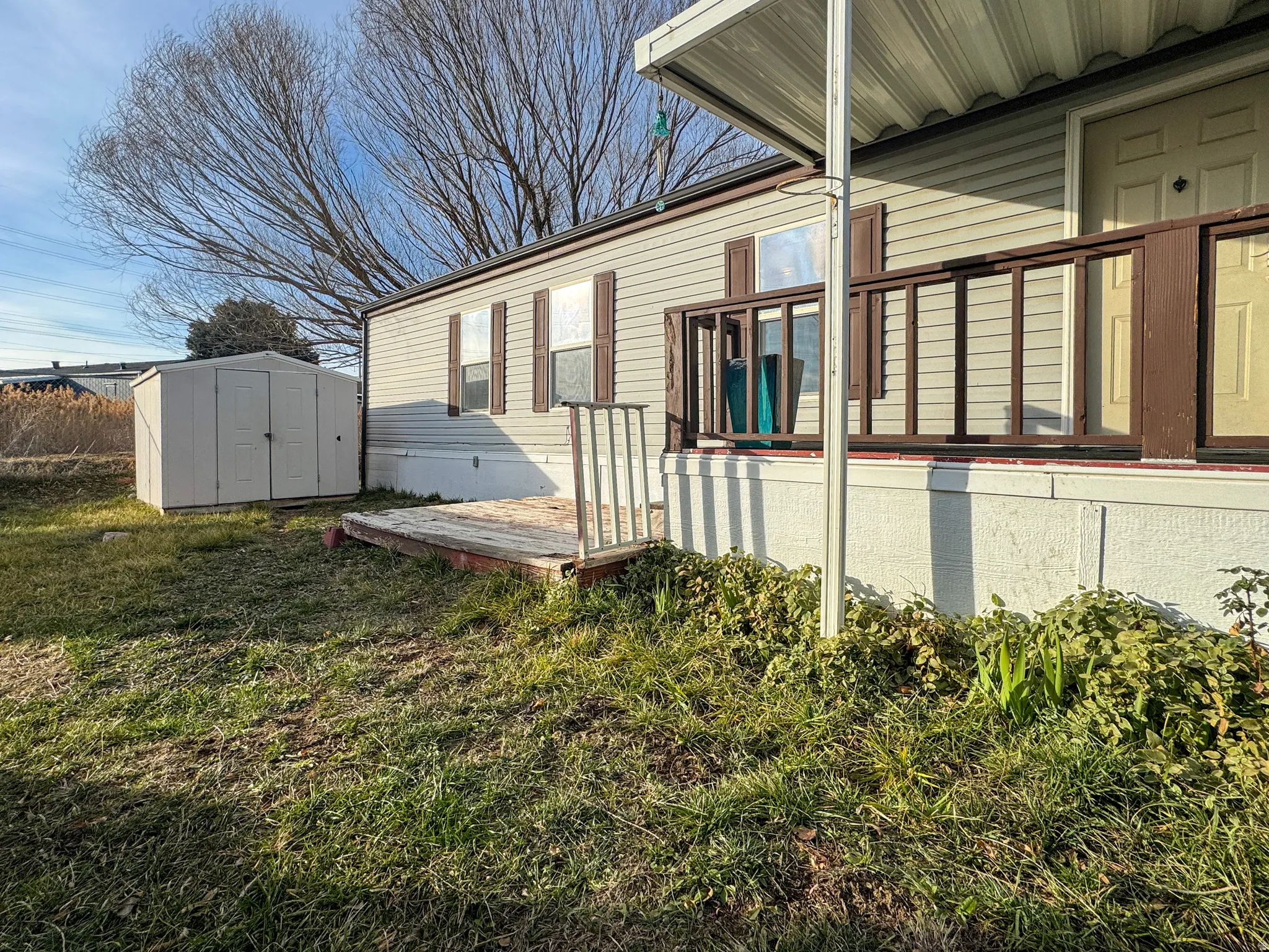 View of home's exterior with a storage shed, a deck, and a yard