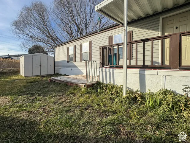 View of home's exterior with a storage shed, a deck, and a yard
