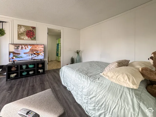 Bedroom featuring a textured ceiling, wood finished floors, and a decorative wall