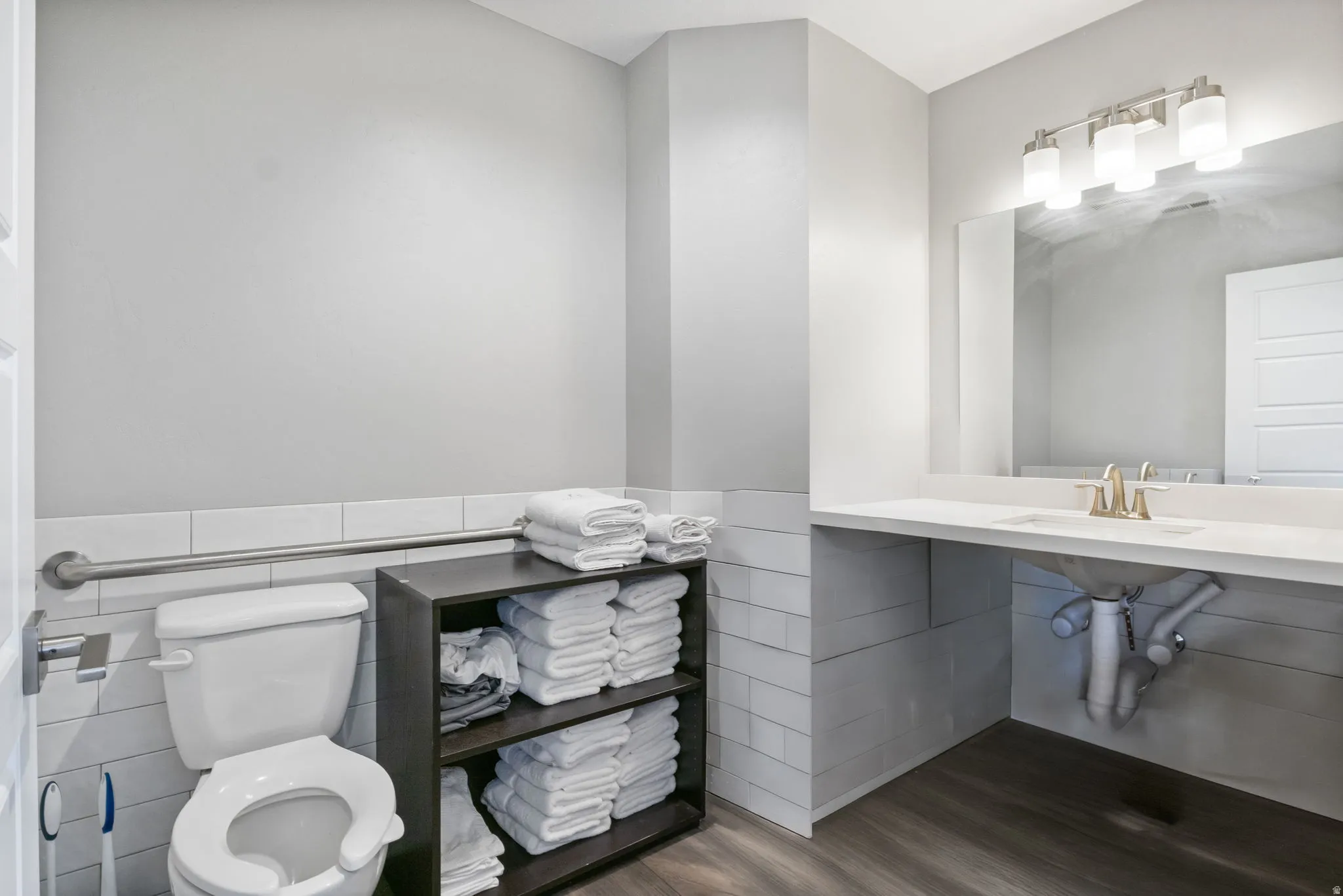 Half bathroom with tile walls, dark wood finished floors, and wainscoting