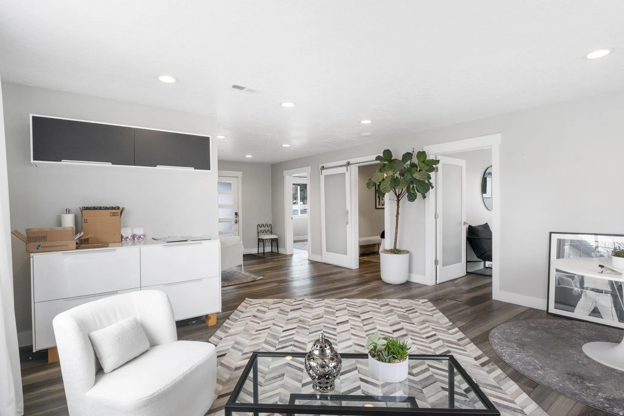 Living area with a barn door, dark wood finished floors, and recessed lighting