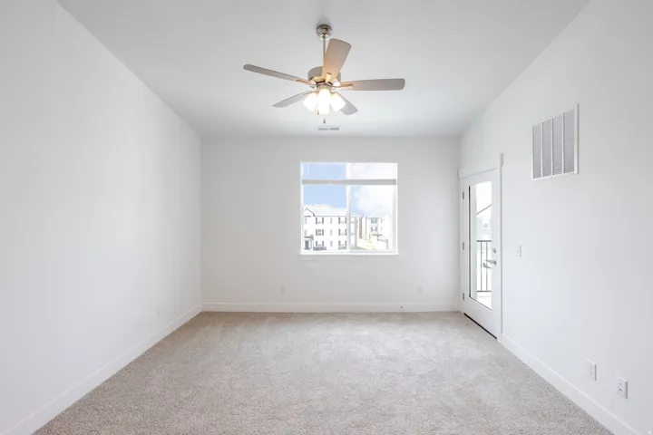 Carpet flooring, white walls, ceiling fan with integrated lighting, window, and a glass-paneled door