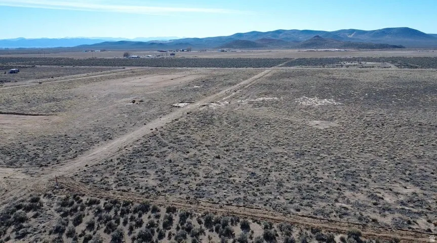 Aerial view of property and surrounding area featuring a mountain backdrop and rural landscape