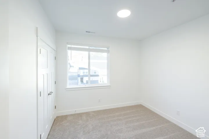 Neutral-toned wall-to-wall carpeting, white walls, recessed ceiling lighting, and double-door closet with paneled detailing