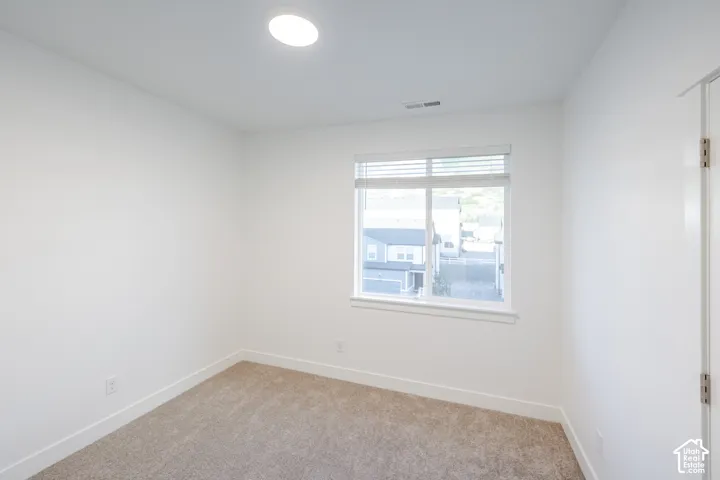 Neutral interior space featuring carpeted flooring, white walls, a single-pane sliding window with horizontal blinds, and a recessed ceiling light