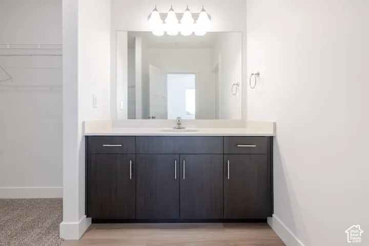 Dark-toned vanity with integrated cabinetry, solid-surface countertop, rectangular undermount sink, wall-mounted vanity lighting, and oversized wall-mounted mirror