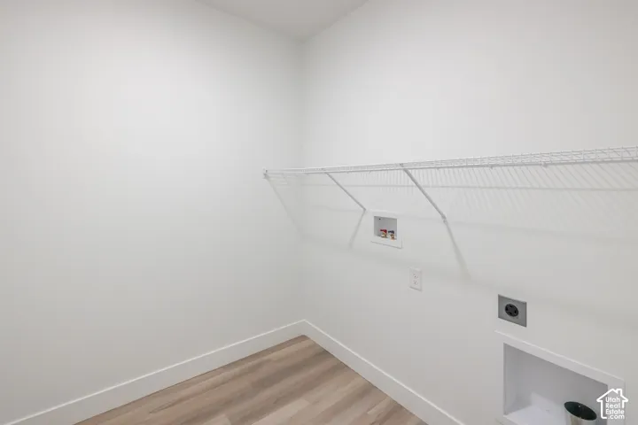 Laundry area featuring wood-finish flooring, white walls, and built-in white wire shelving