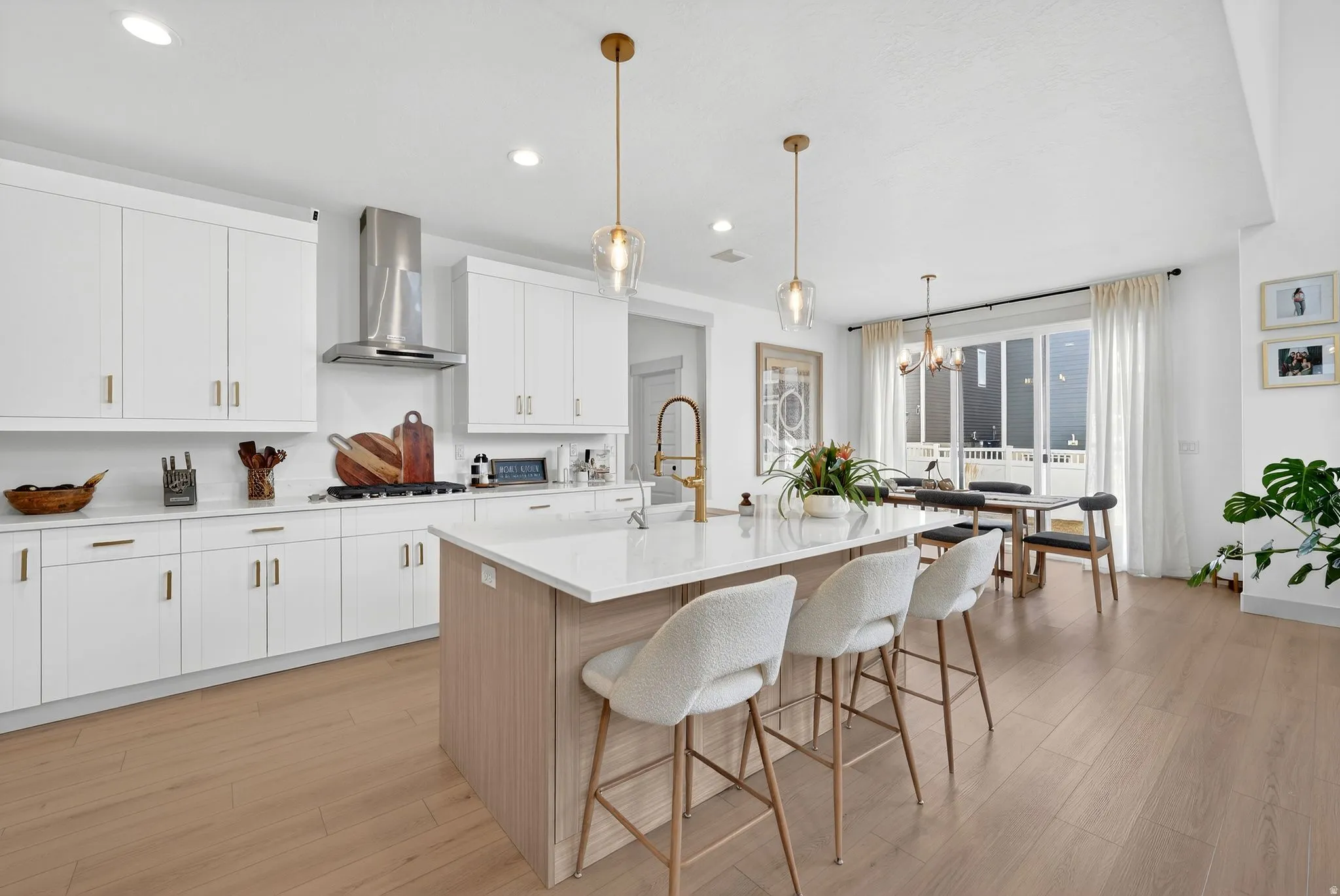 Two tone kitchen with dual tone cabinets, a breakfast bar, light wood finished floors, a center island with sink, and light stone countertops