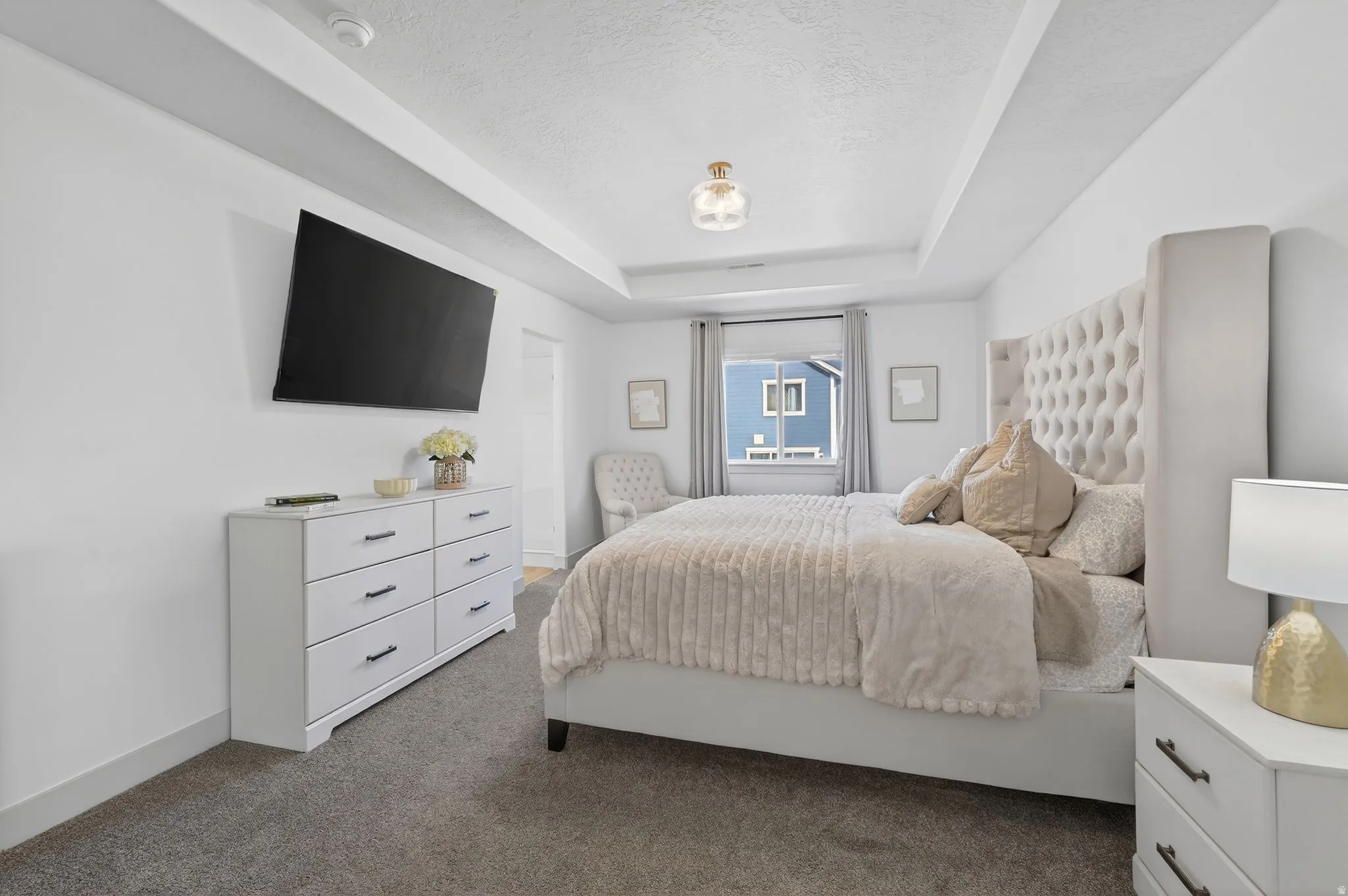 Bedroom with a raised ceiling, carpet flooring, and a textured ceiling