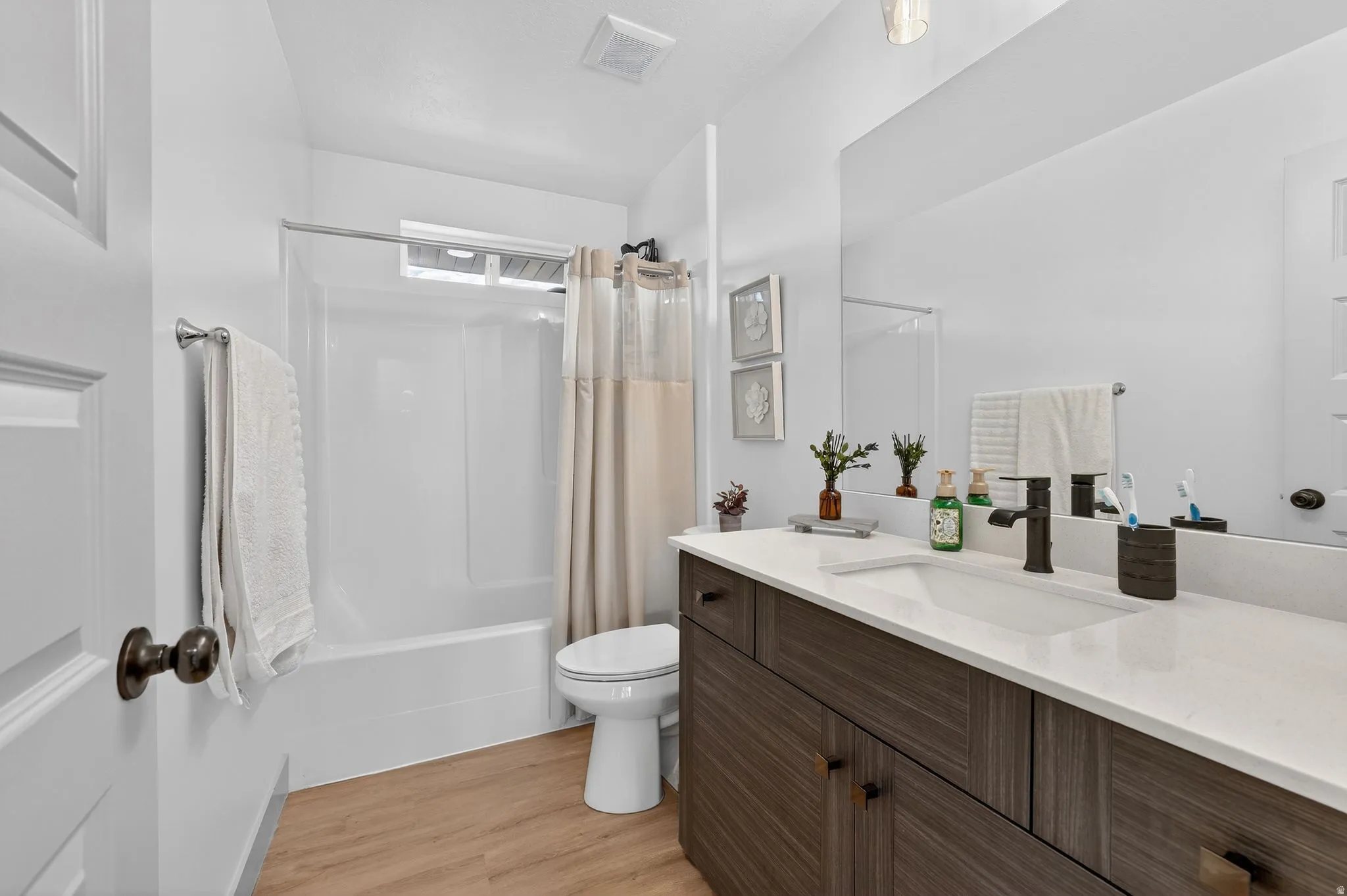 Bathroom featuring vanity, shower / bath combo, and light wood-style flooring