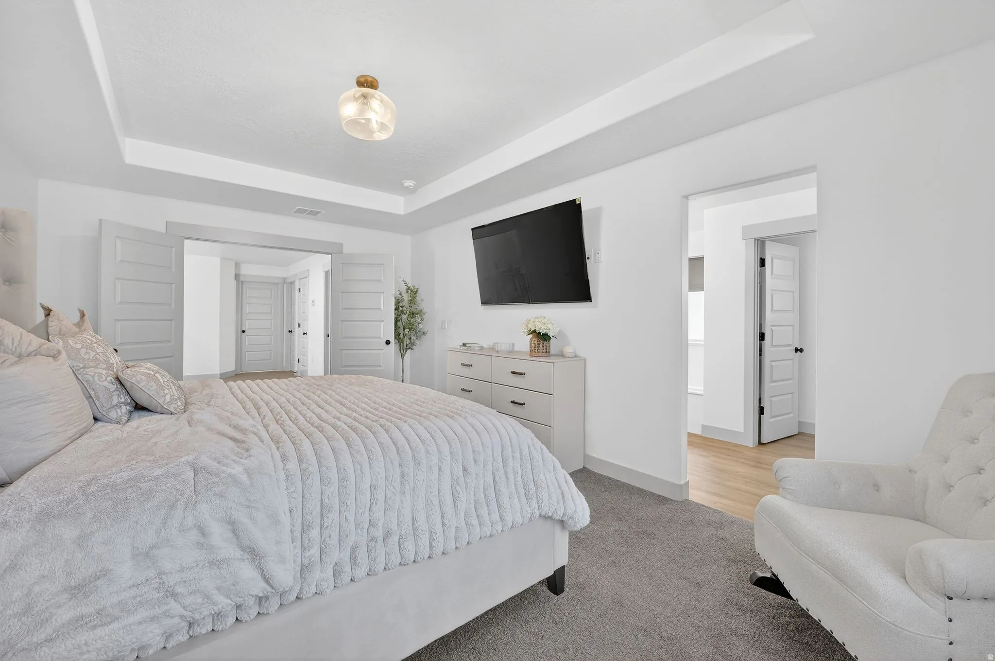 Bedroom featuring light carpet and a raised ceiling