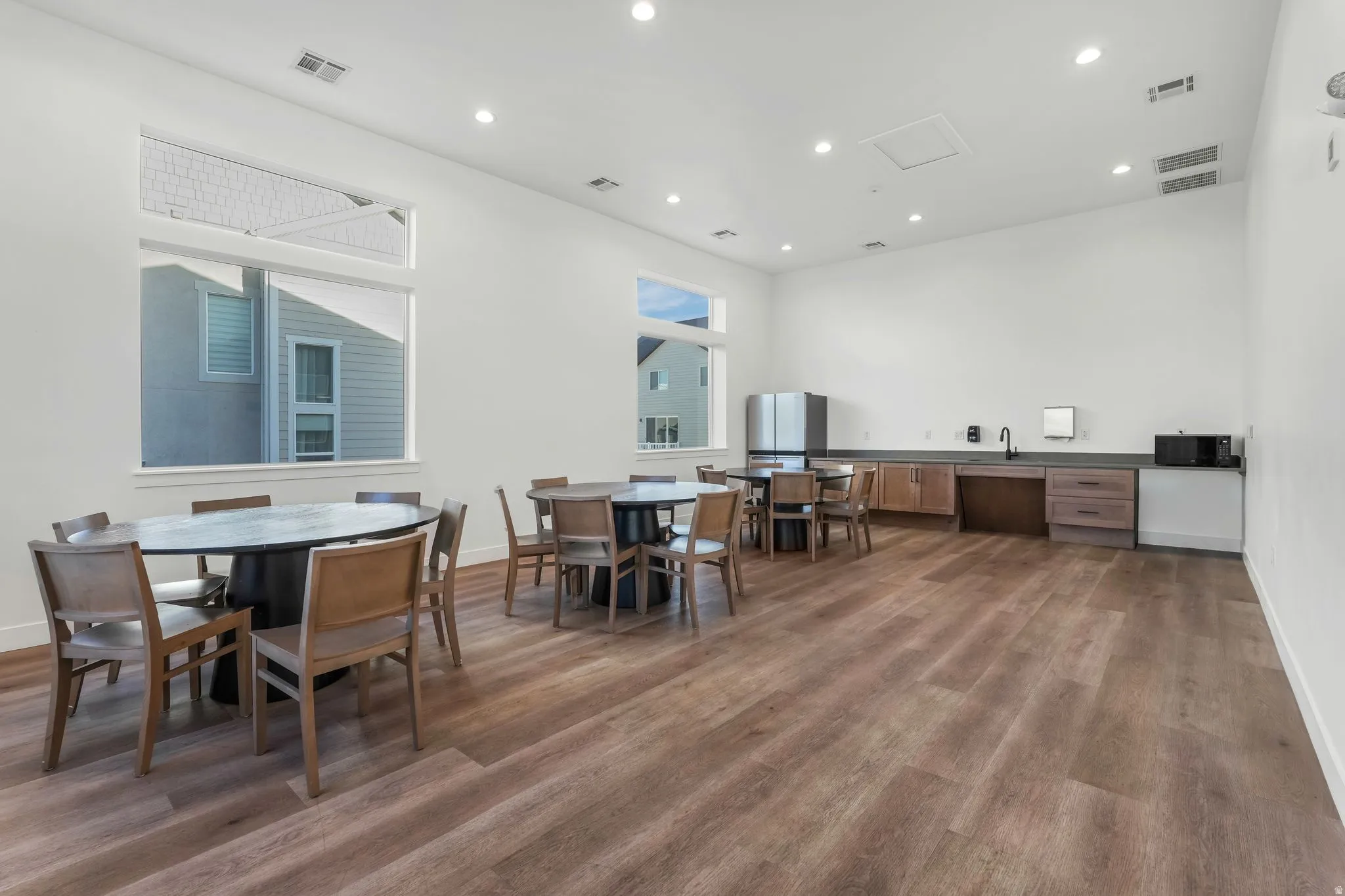 Dining area with dark wood-style floors, recessed lighting, and a high ceiling