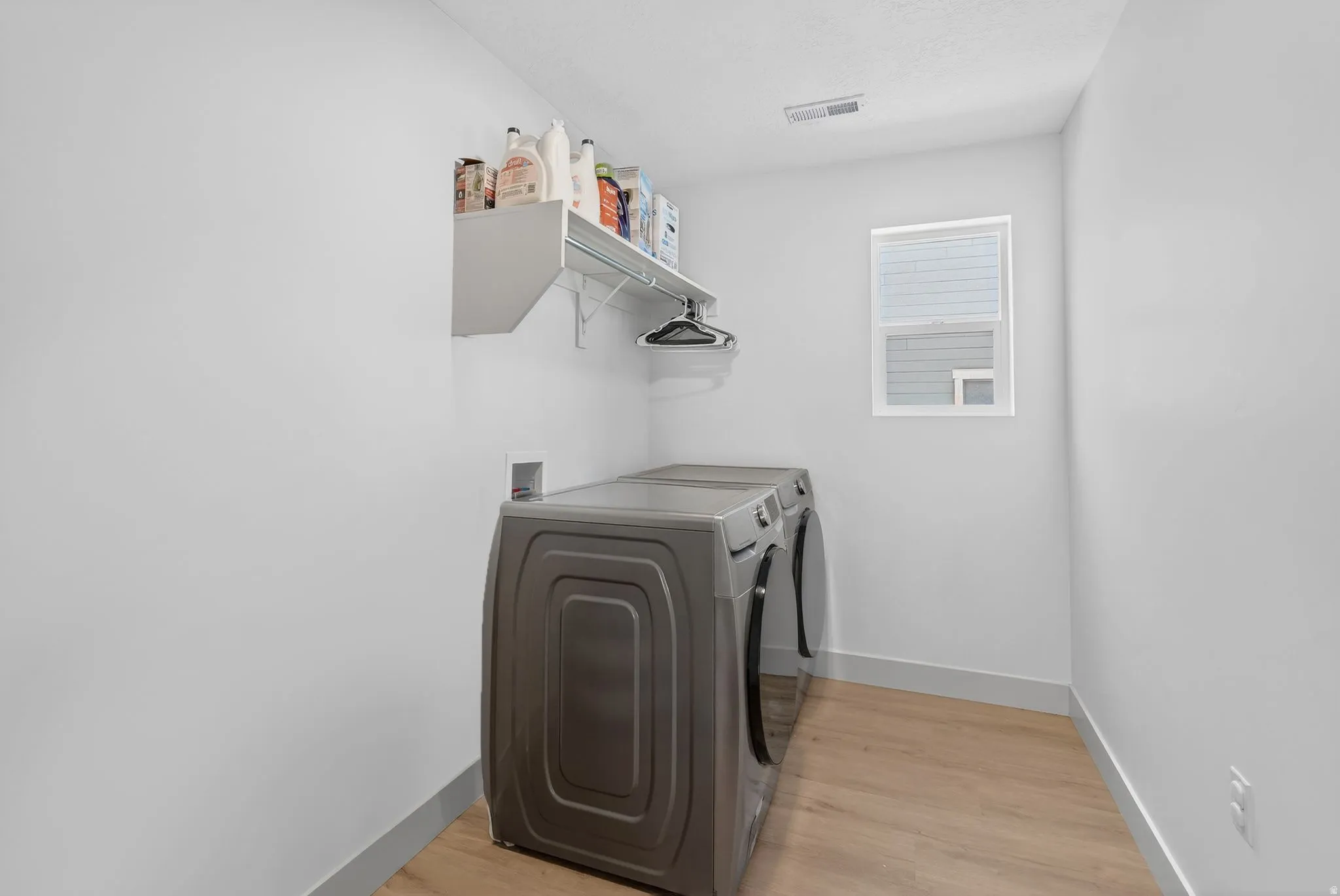 Laundry area with light wood-type flooring and washer and dryer