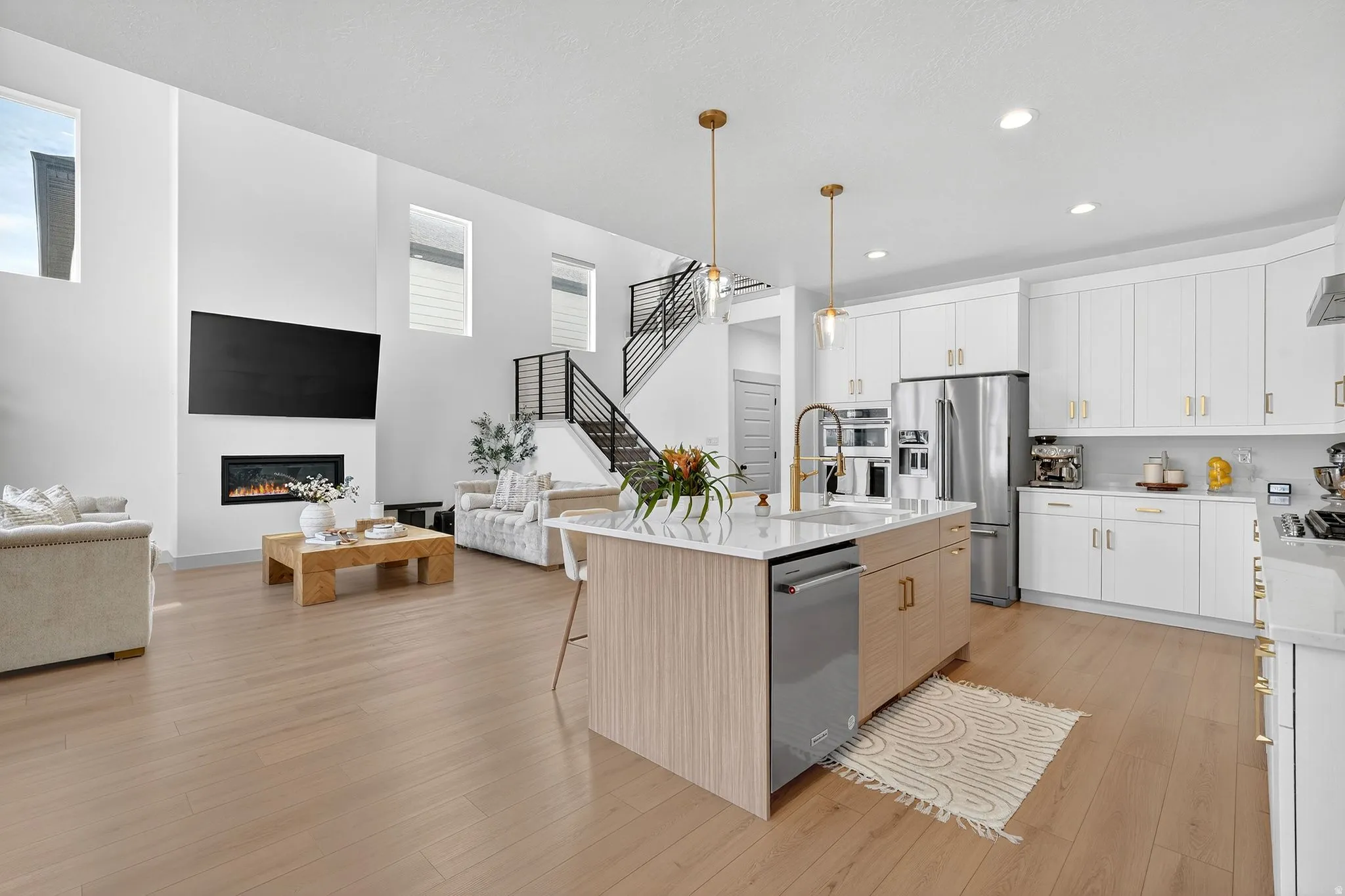 Dual tone kitchen featuring a kitchen bar, open floor plan, stainless steel appliances, hanging light fixtures, and light wood finished floors