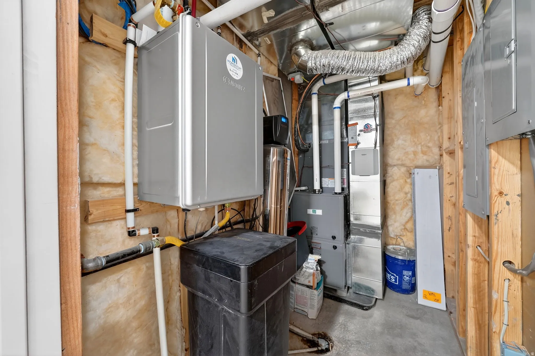 Utility room with electric panel, water heater, and heating unit