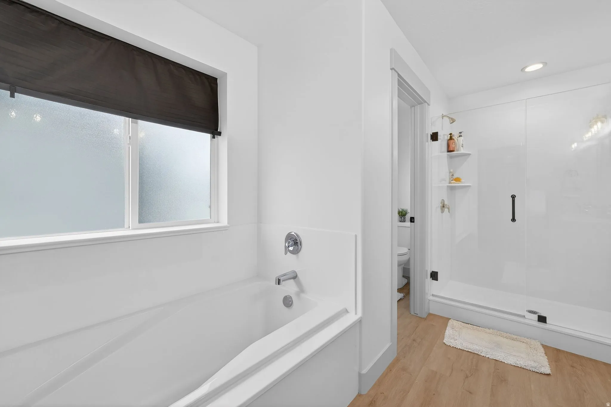 Full bathroom featuring a garden tub, light wood-type flooring, a shower stall, and recessed lighting