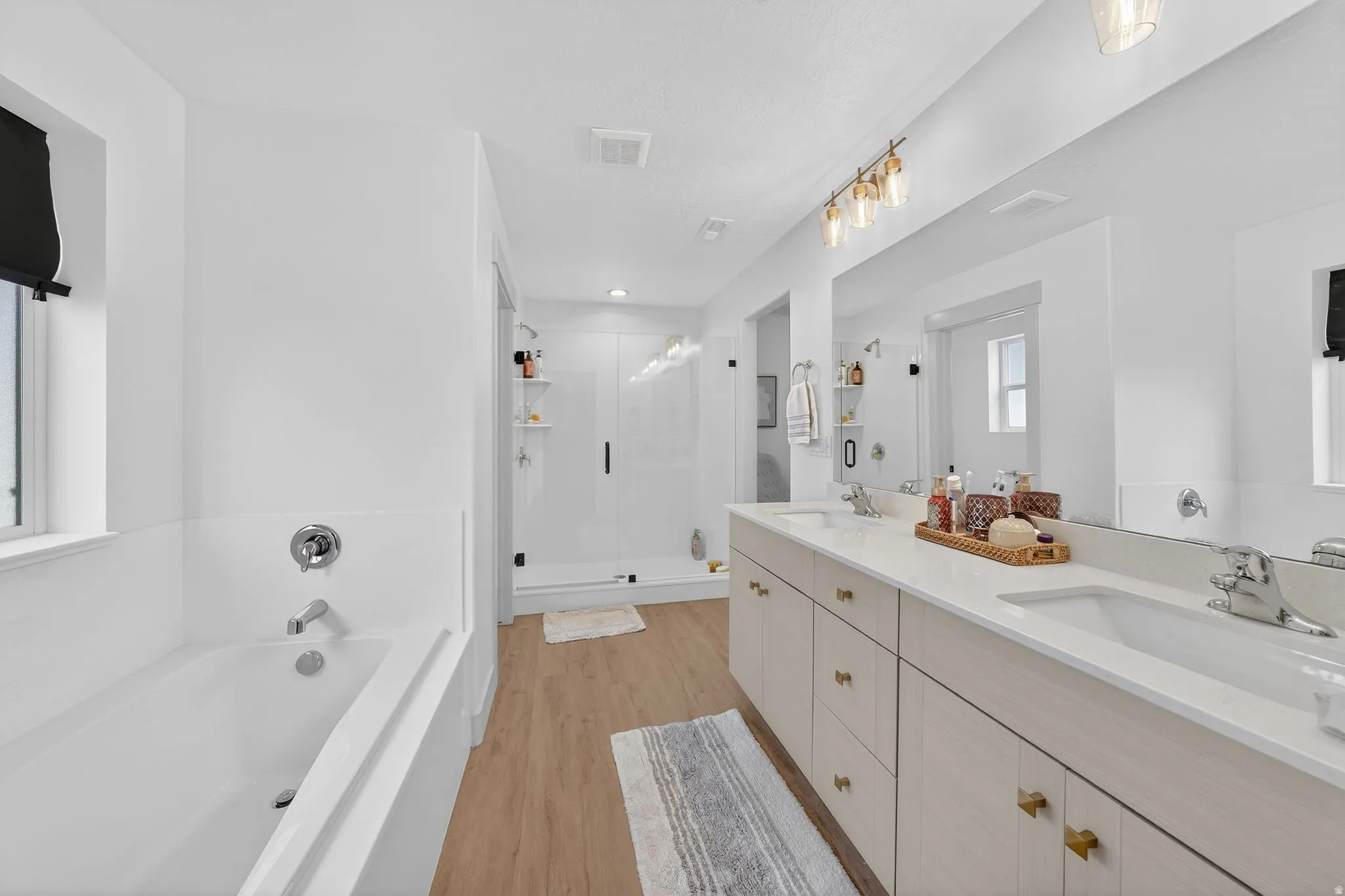 Bathroom featuring a garden tub, double vanity, plenty of natural light, and a stall shower