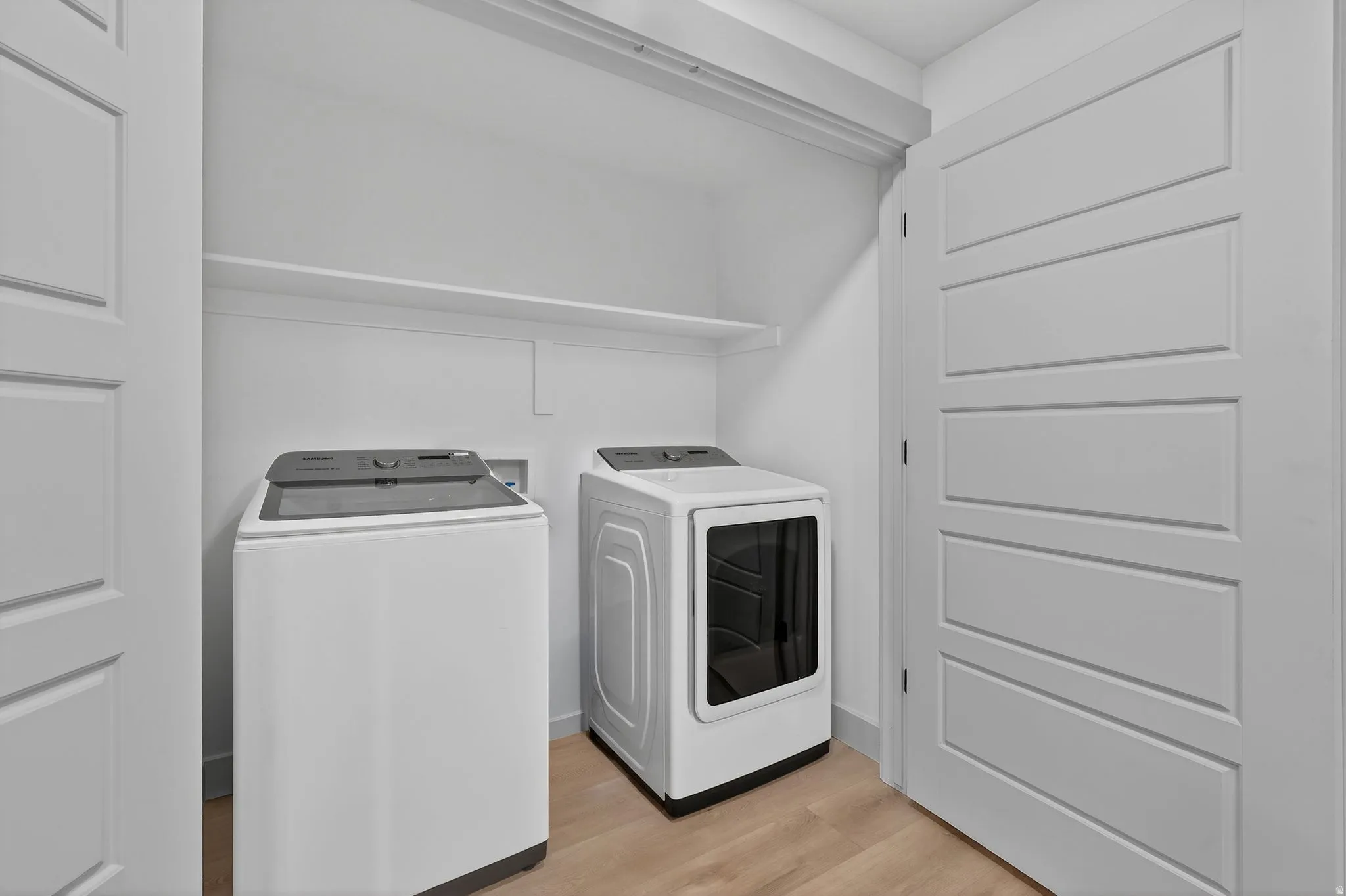 Laundry area with light wood finished floors and washing machine and clothes dryer