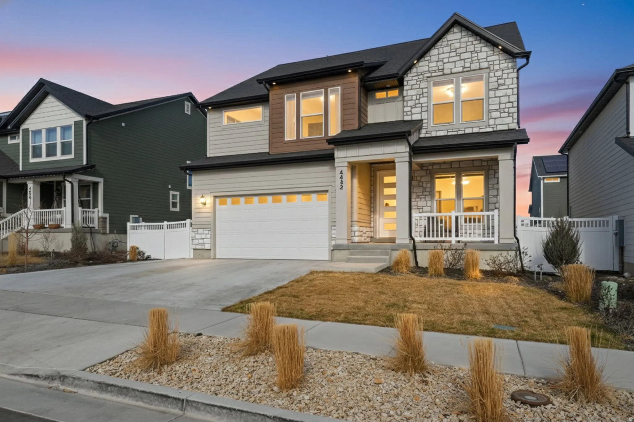 View of front facade with stone siding, driveway, an attached garage, and a porch