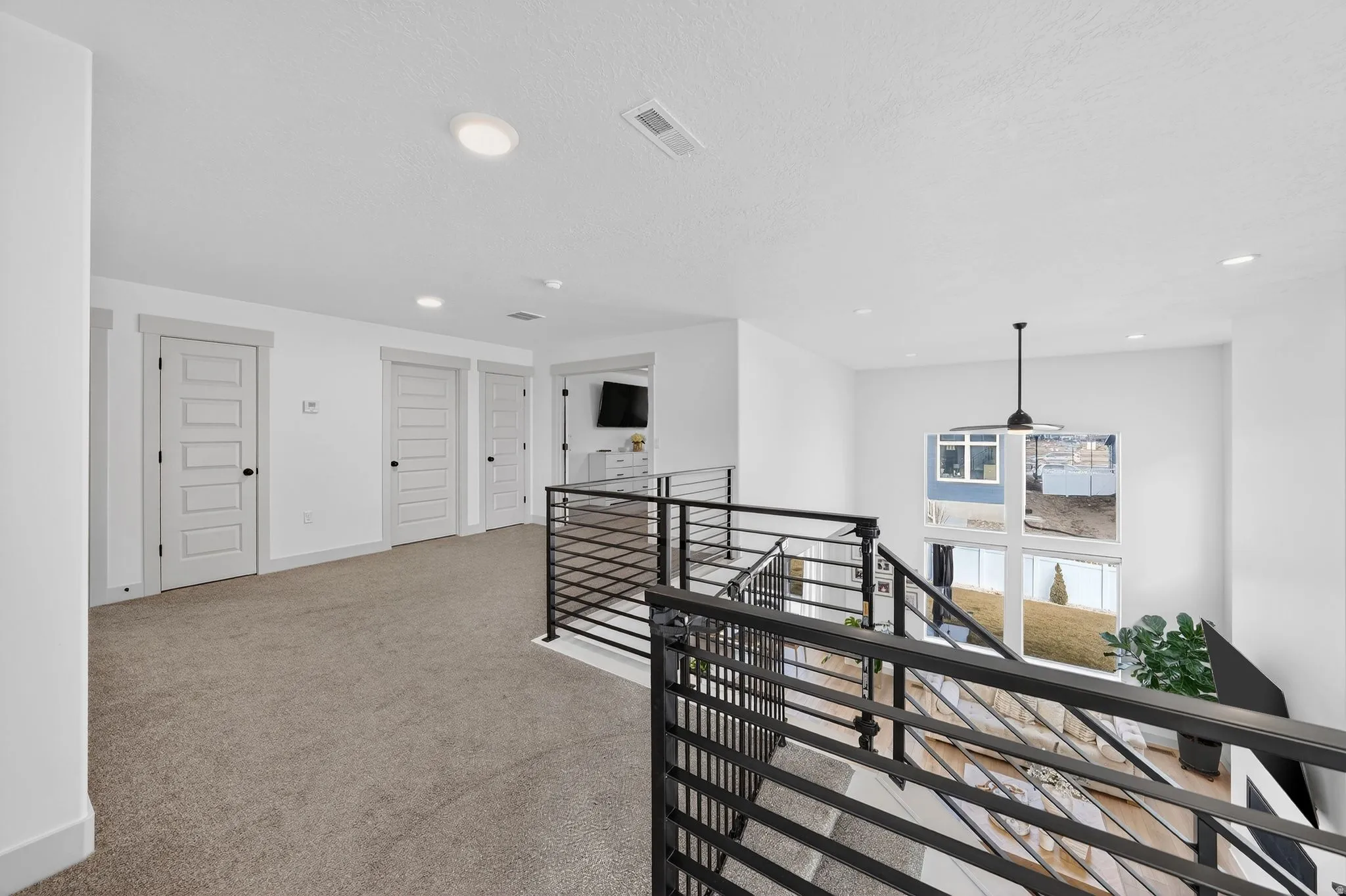 Corridor featuring an upstairs landing, light carpet, a textured ceiling, and recessed lighting