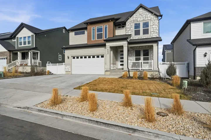 View of front of home featuring stone siding, a garage, concrete driveway, and a porch