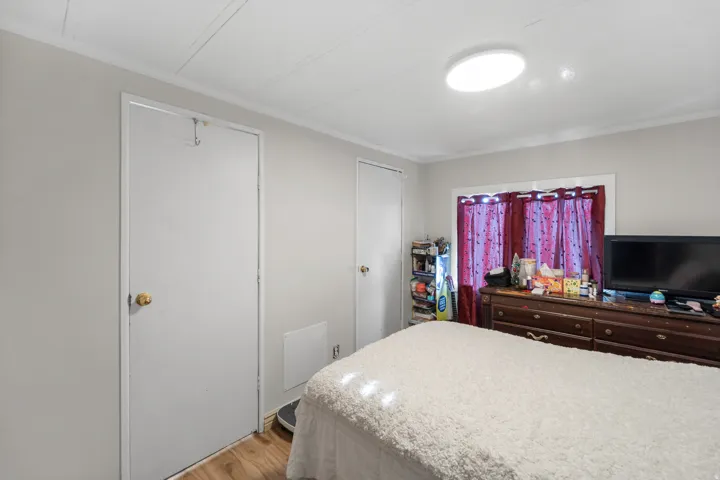 Bedroom with light wood finished floors, two closets, and crown molding