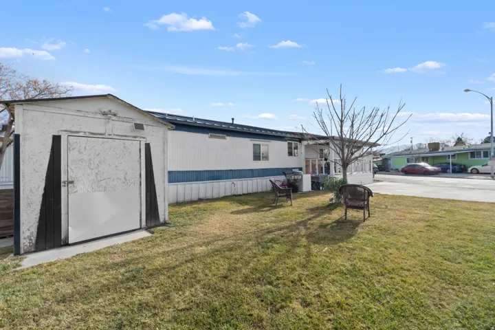 View of front of home with a storage shed, roof mounted solar panels, and a front yard