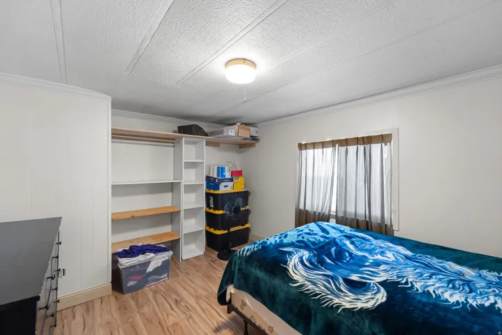 Bedroom with light wood-style floors, crown molding, and a textured ceiling