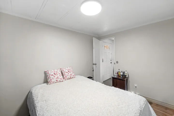 Bedroom with crown molding and wood finished floors