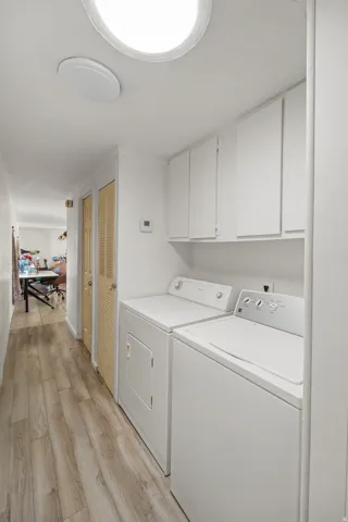 Laundry area featuring light wood finished floors, separate washer and dryer, and cabinet space