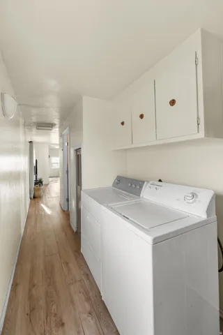Laundry room featuring light wood-style flooring, washing machine and clothes dryer, and cabinet space