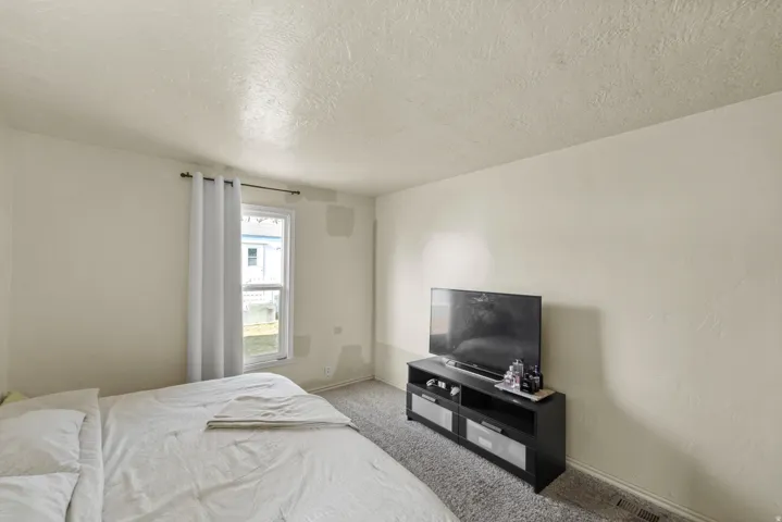 Carpeted bedroom with a textured ceiling and baseboards