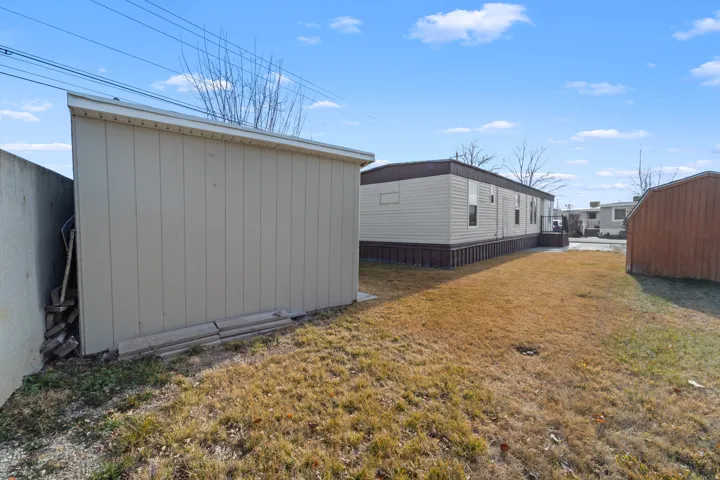 View of side of property featuring a storage unit and a lawn
