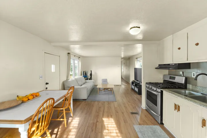 Kitchen with stainless steel gas range, light wood-style floors, white cabinets, open floor plan, and a textured ceiling