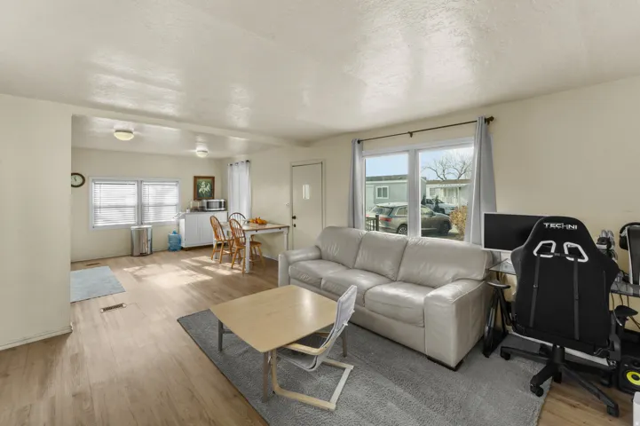 Living area with light wood-style flooring, a textured ceiling, and healthy amount of natural light